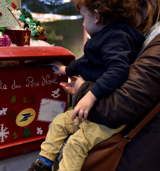 Atelier de noël à l’hôpital Necker, un enfant et sa mère déposant une lettre dans la boite aux lettres décorés